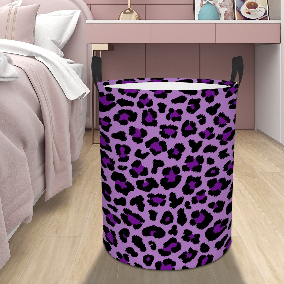 Purple leopard print laundry basket on a wooden floor next to a bed.