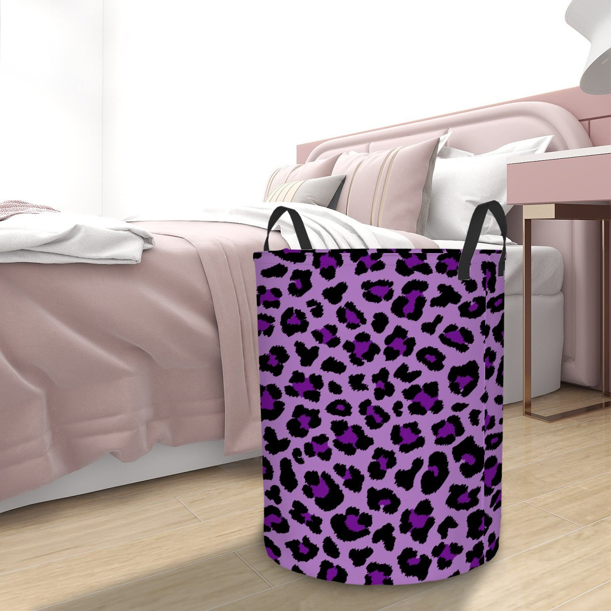 Purple leopard print laundry basket on a wooden floor with a bed in the background